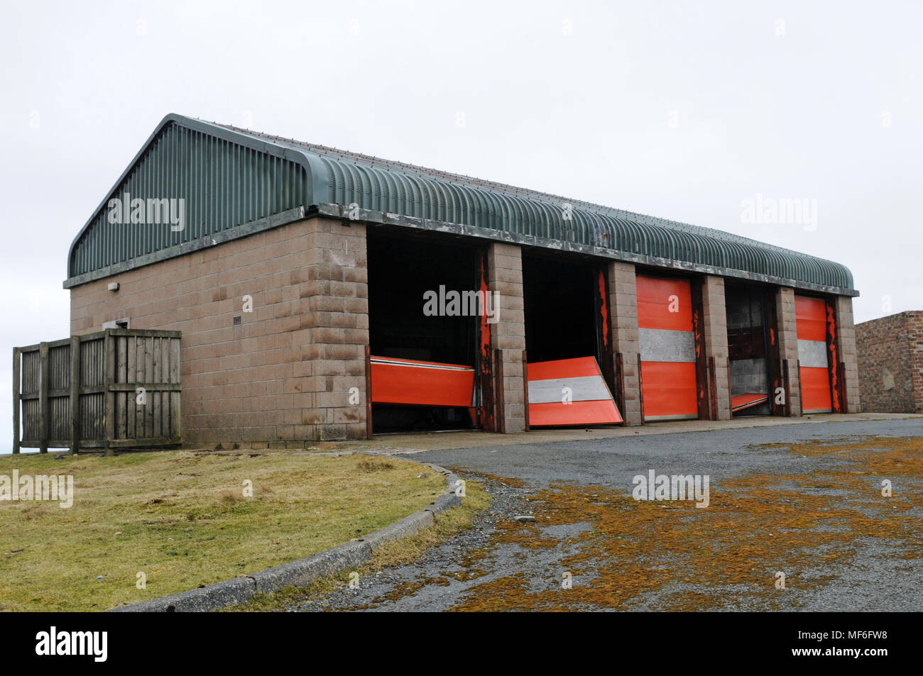 Derelict fire station garage with doors broken blow in Stock Photo