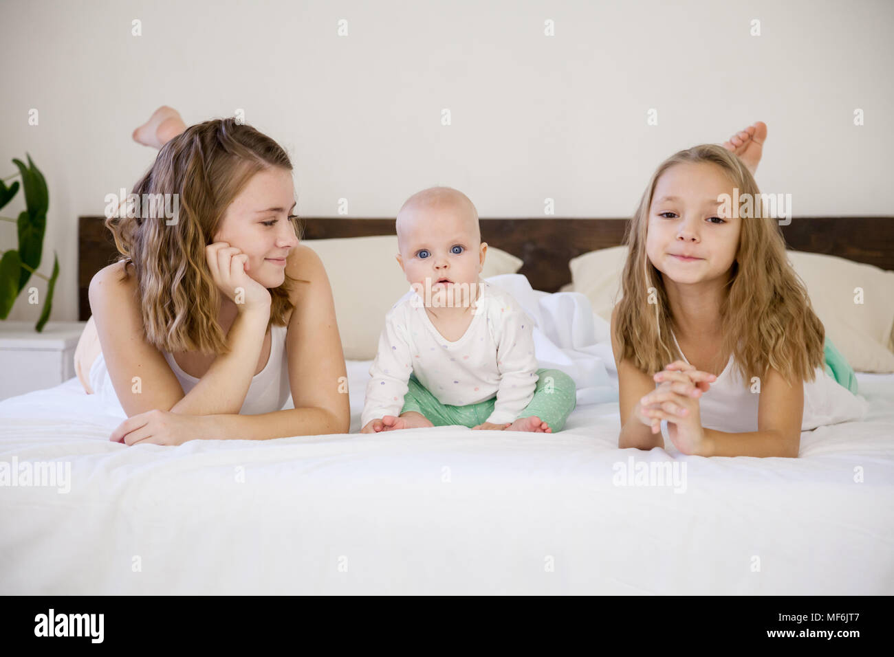 three girls play sisters in the morning in the bedroom on the bed Stock Photo