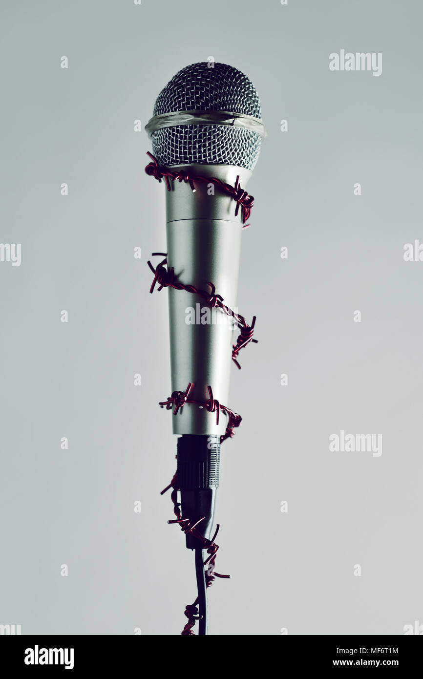 a microphone encircled by a red barbed wire, depicting the idea of the repression of the mass media or the lack of the freedom of speech Stock Photo