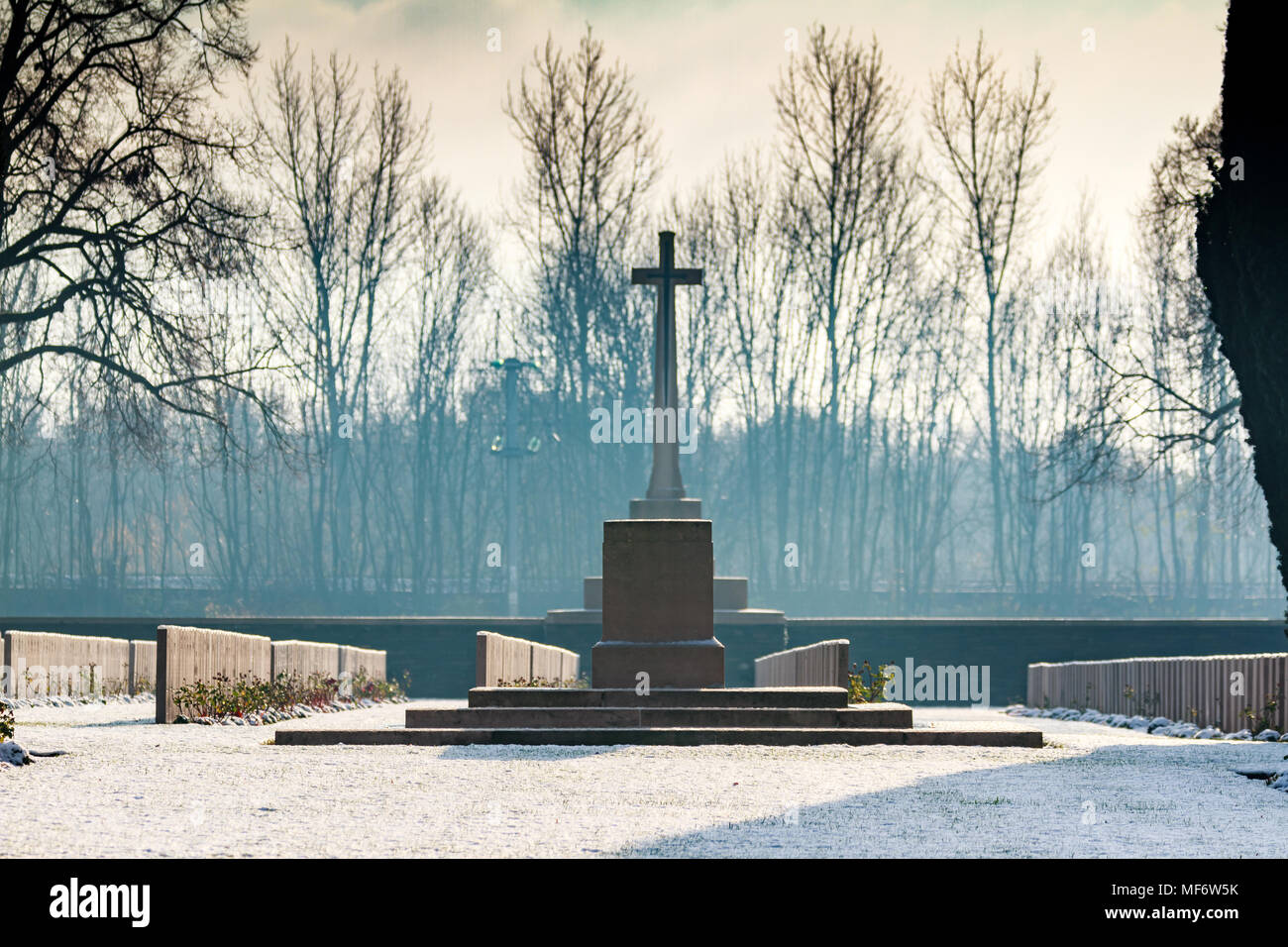 A misty morning at the snow covered Commonwealth War Graves Commissions (CWGC) Brown's Copse Cemetery. A Cenotaph behind a Stone of Remembrance. Stock Photo