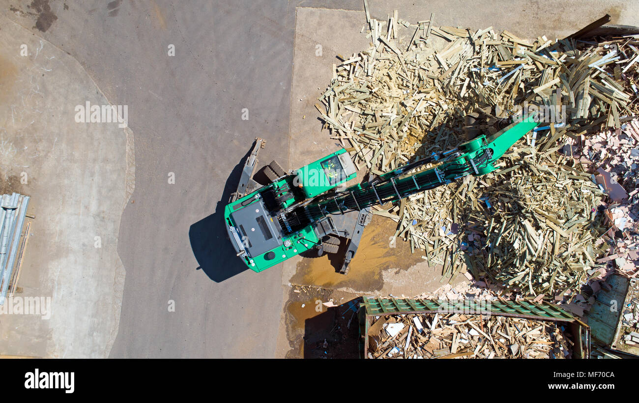 Aerial photo of a crane with a huge claw in front of a wood scrap heap Stock Photo