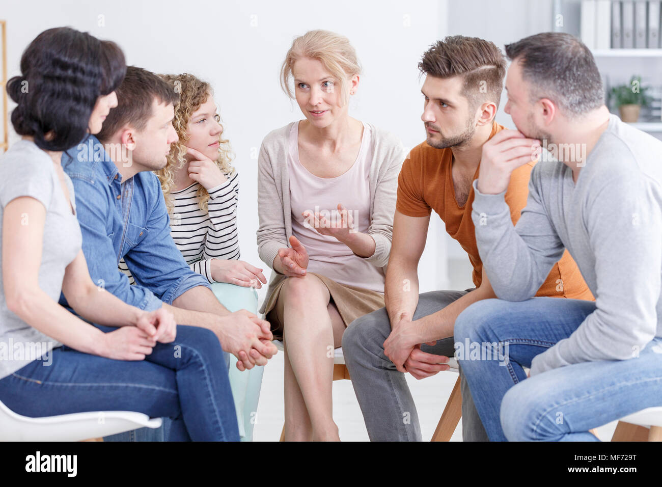 Female psychologist explaining the process of healing to a group of people fighting depression Stock Photo