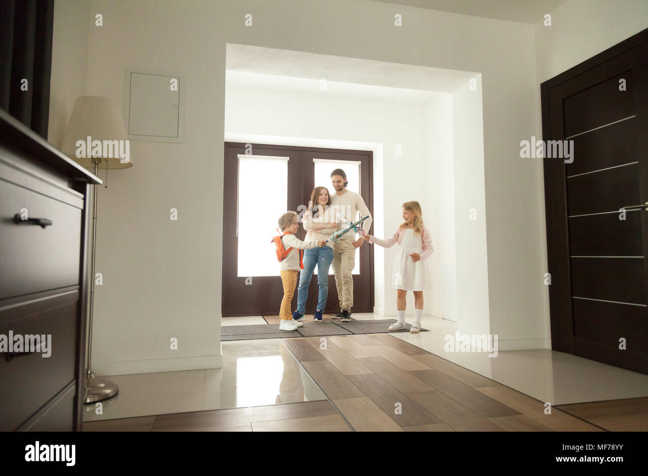 Cute kids playing umbrellas getting ready for walk at home  Stock Photo