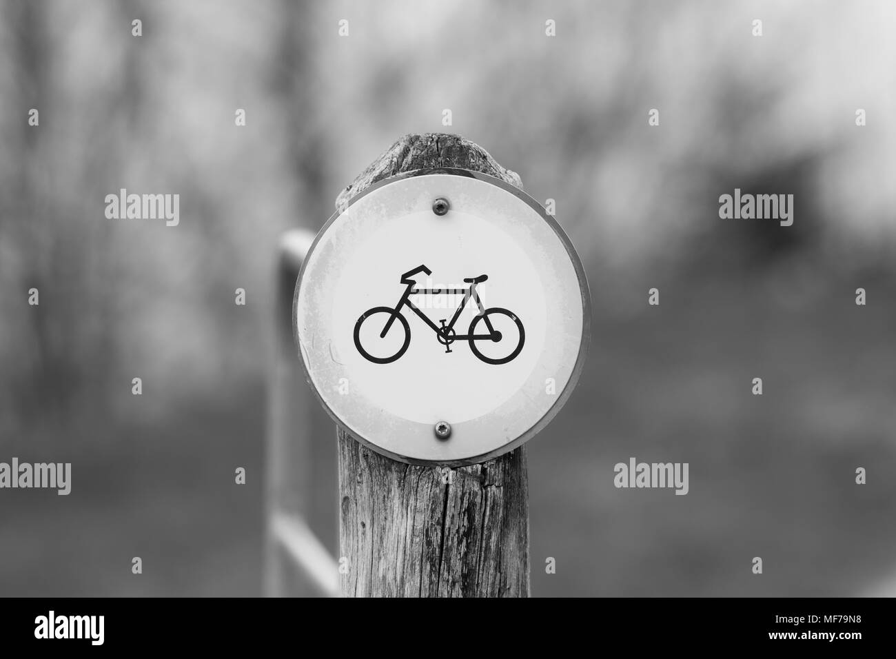 Old and pale no bicycle sign on a wooden pillar in nature Stock Photo