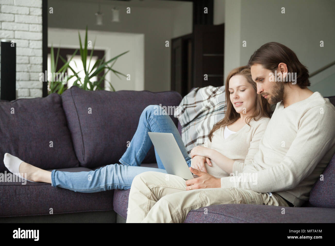 Young couple using laptop discussing news or doing online shoppi Stock Photo