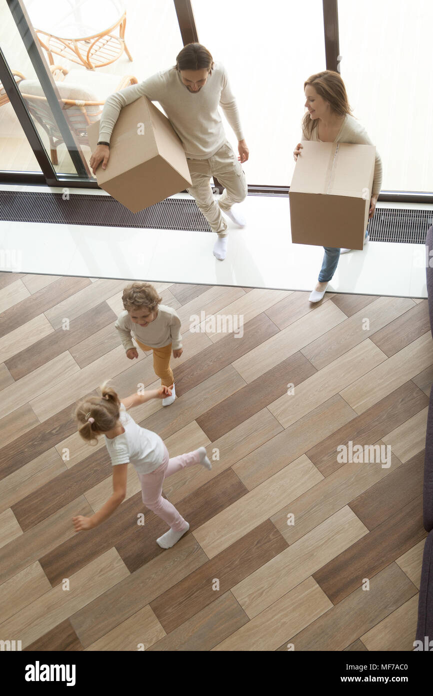 Parents holding boxes, children playing on moving day, top view Stock Photo