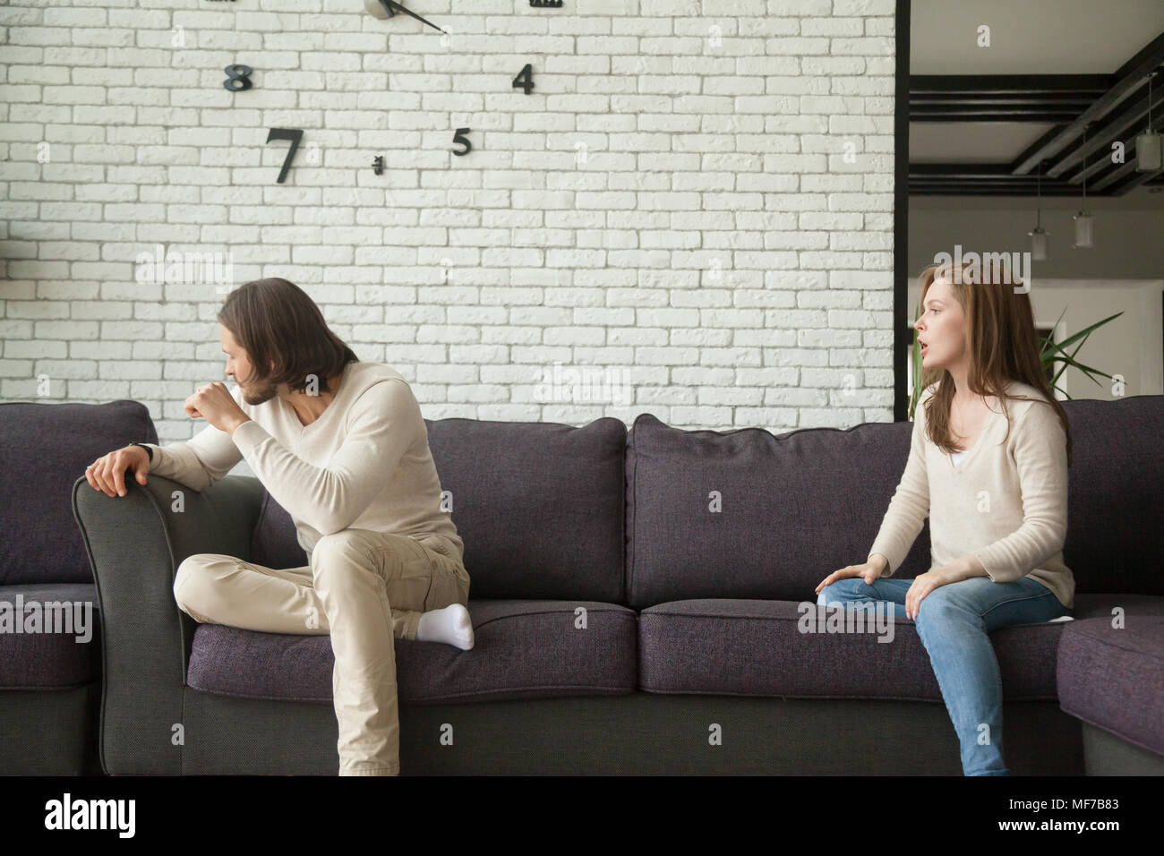 Frustrated husband ignoring angry wife avoiding argument sitting Stock Photo