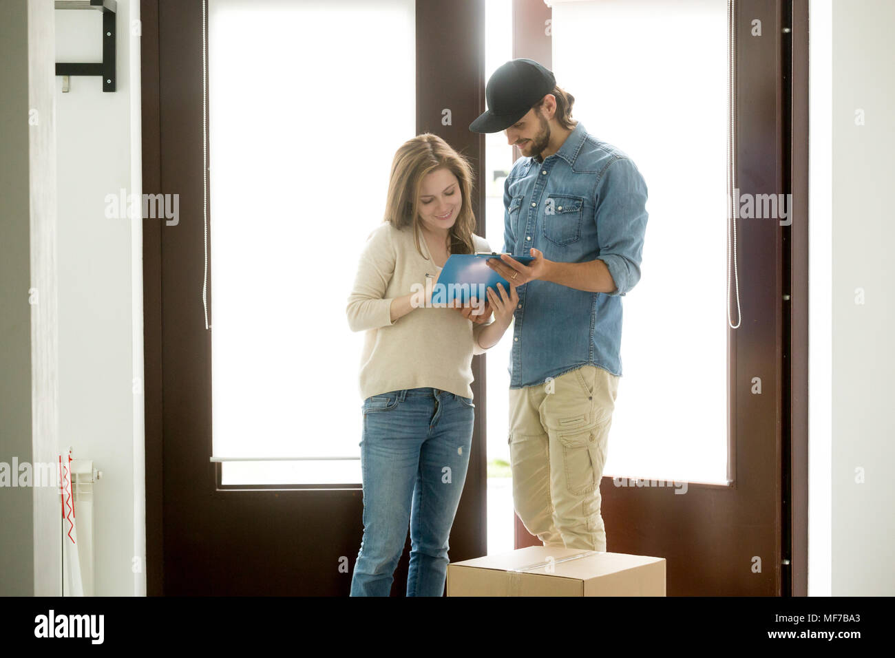 Woman putting signature receiving parcel from delivery man at ho Stock Photo