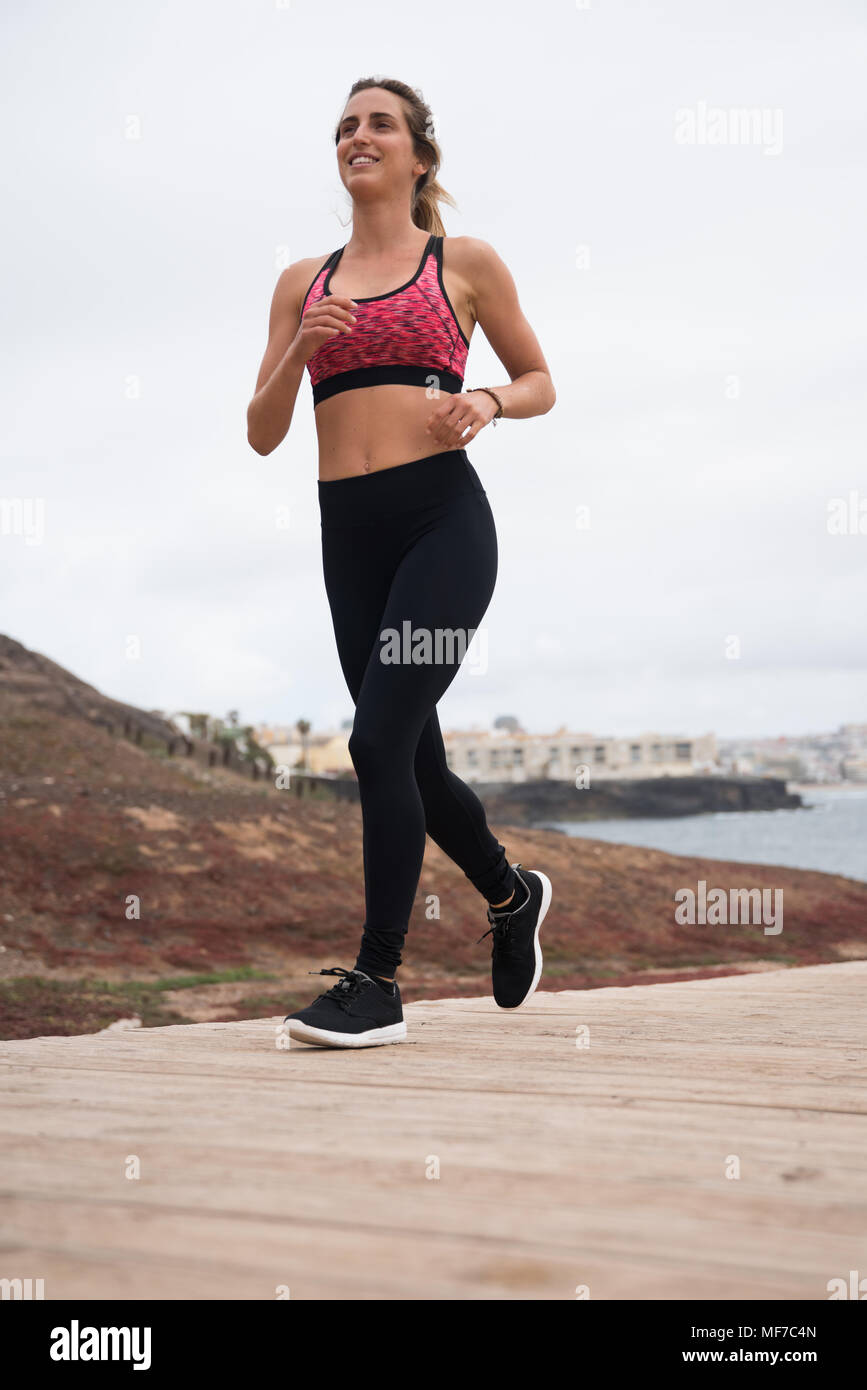 Young pretty blonde jogging on the boarwalk wearing black tights