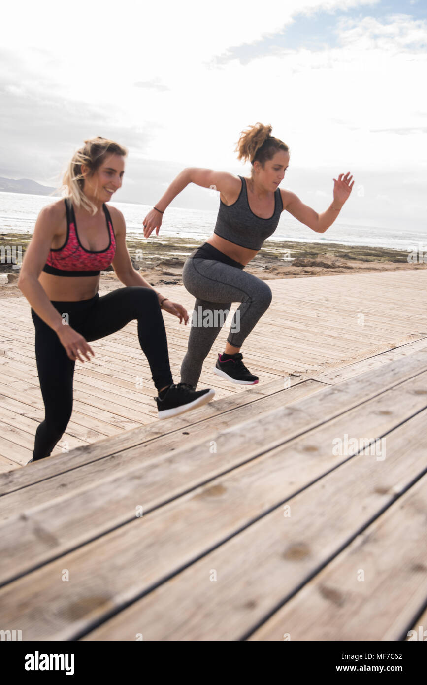 Pretty young women doing fitness training on the seaside boardwalk Stock Photo