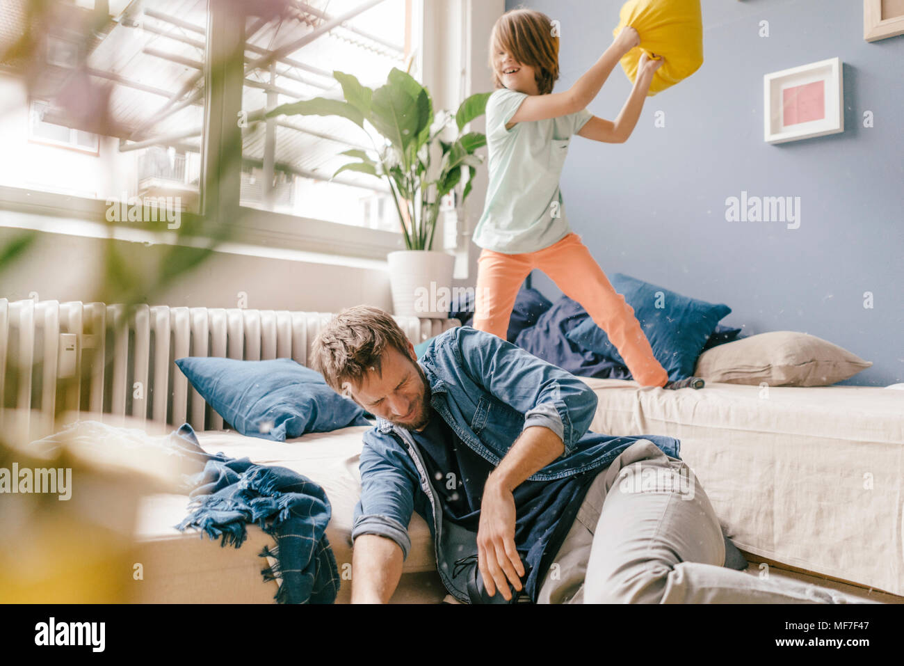 Father and son having a pillow fight at home Stock Photo