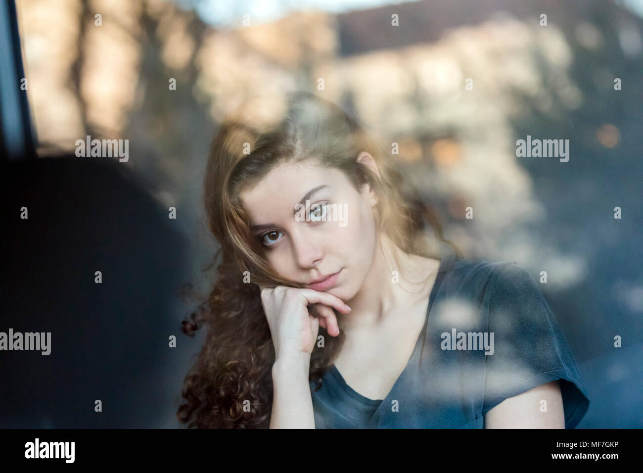 Portrait of pensive teenage girl behing windowpane Stock Photo