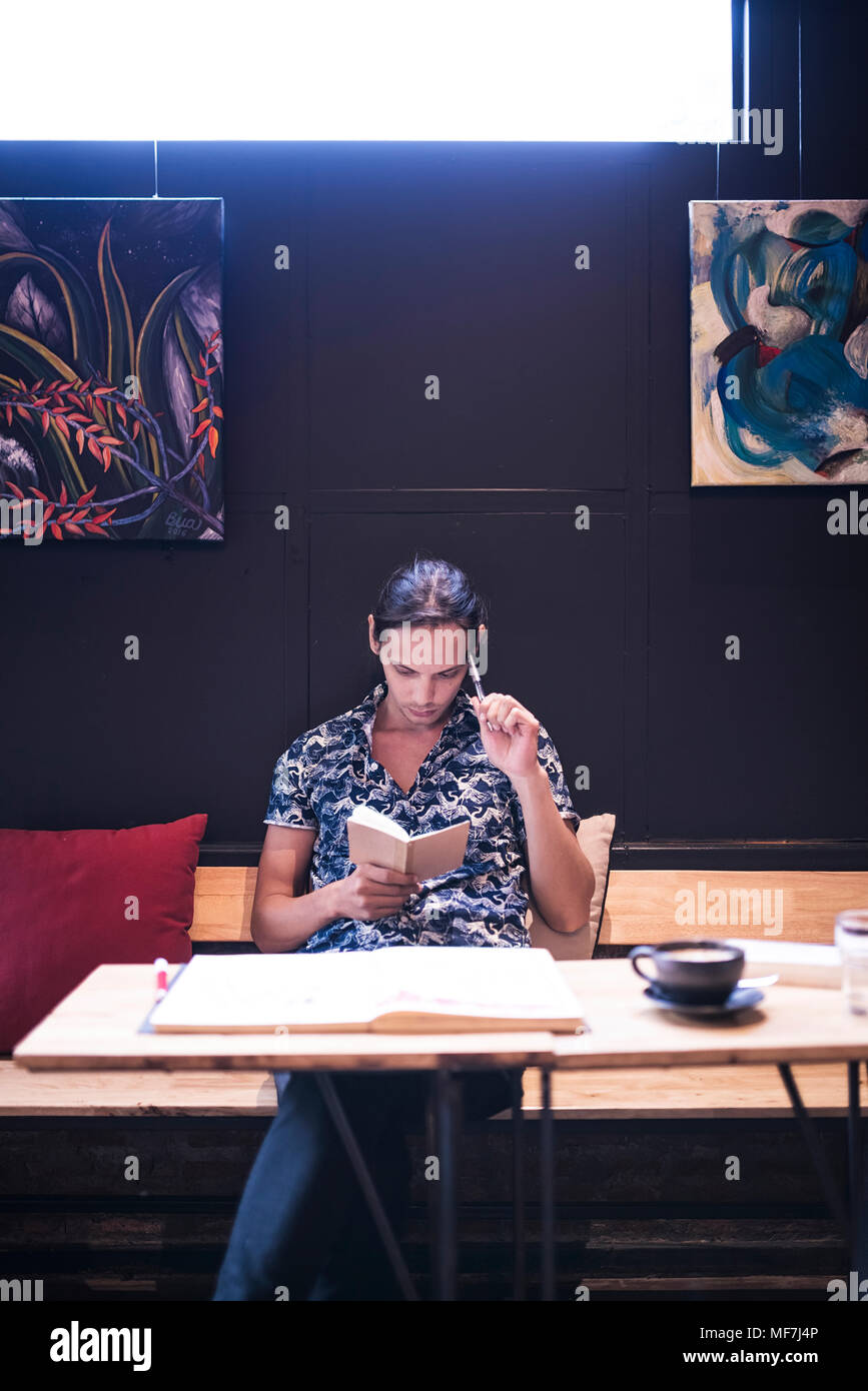 Artist sitting in cafe and reading in small notebook Stock Photo