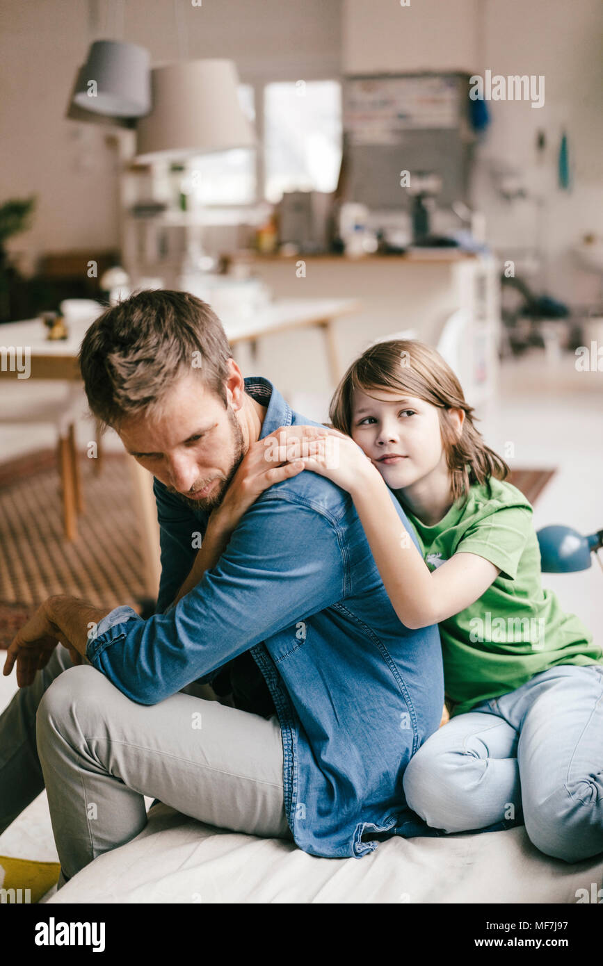 Son consoling sad father at home Stock Photo
