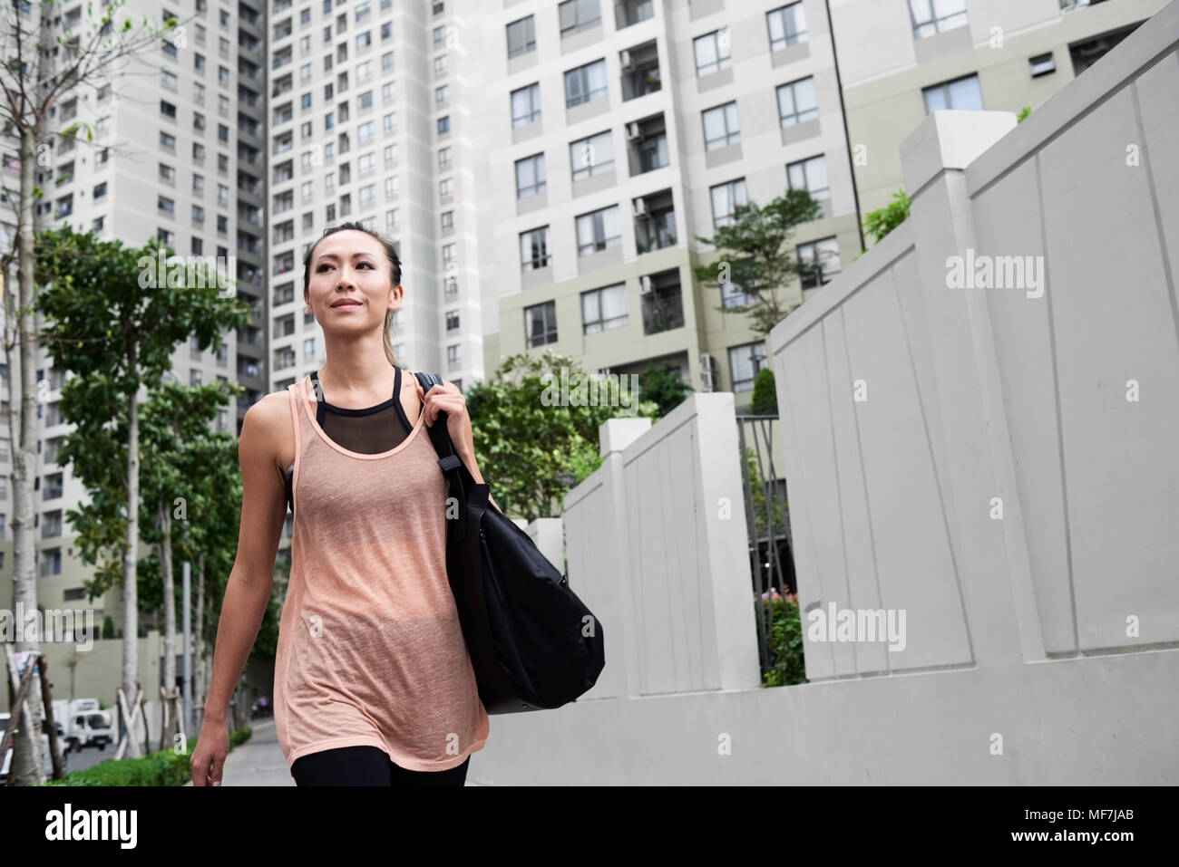 Confident fit woman walking in urban environment Stock Photo