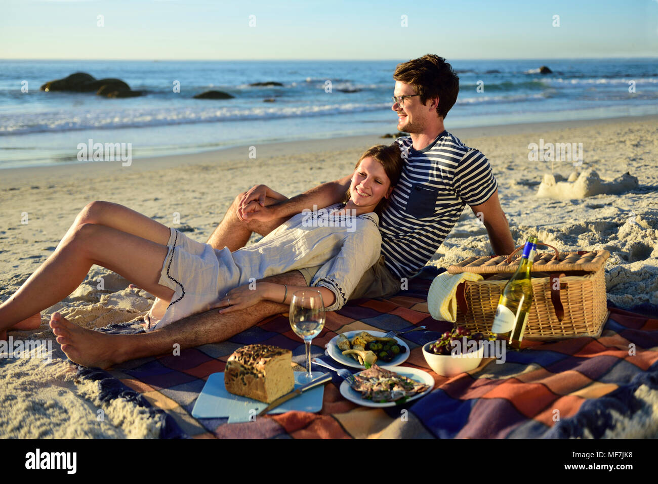 Happy couple having a picnic on the beach Stock Photo