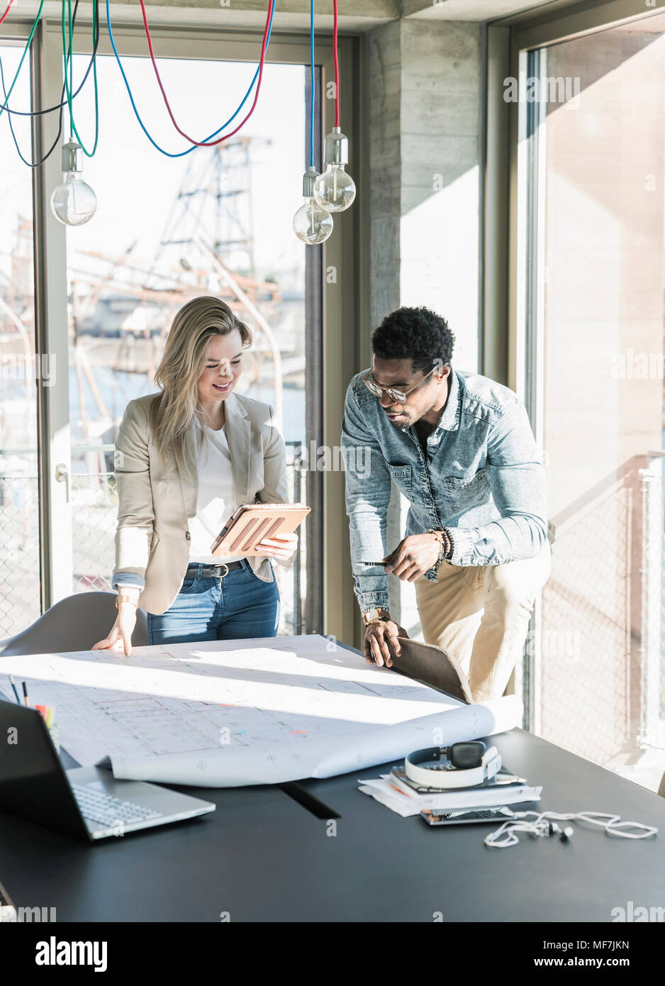 Two colleagues working on plan at table in office Stock Photo
