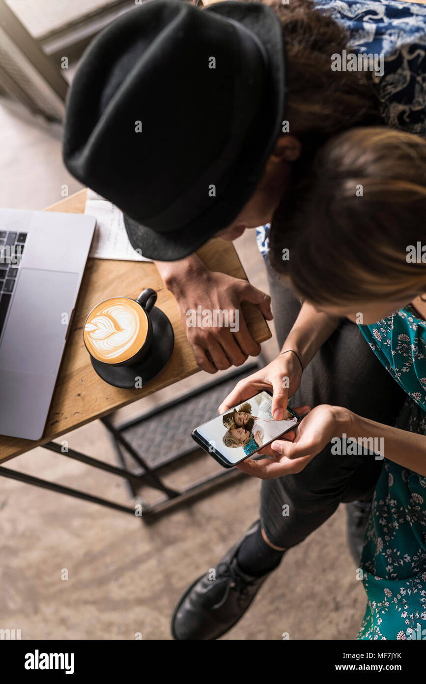Artist couple sitting in cafe and checking the young woman's smartphone Stock Photo