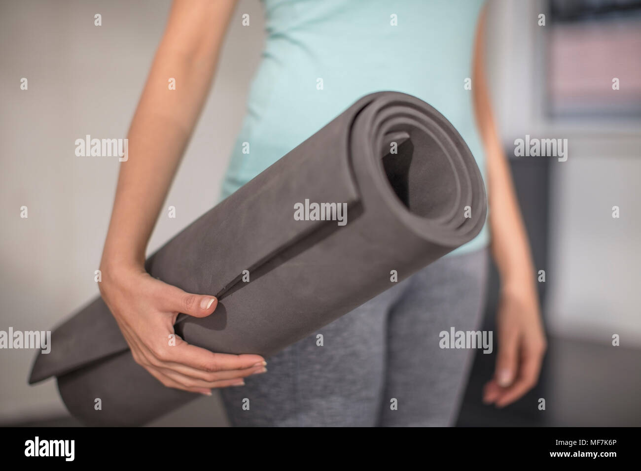 Close-up of woman carrying yoga mat in studio Stock Photo