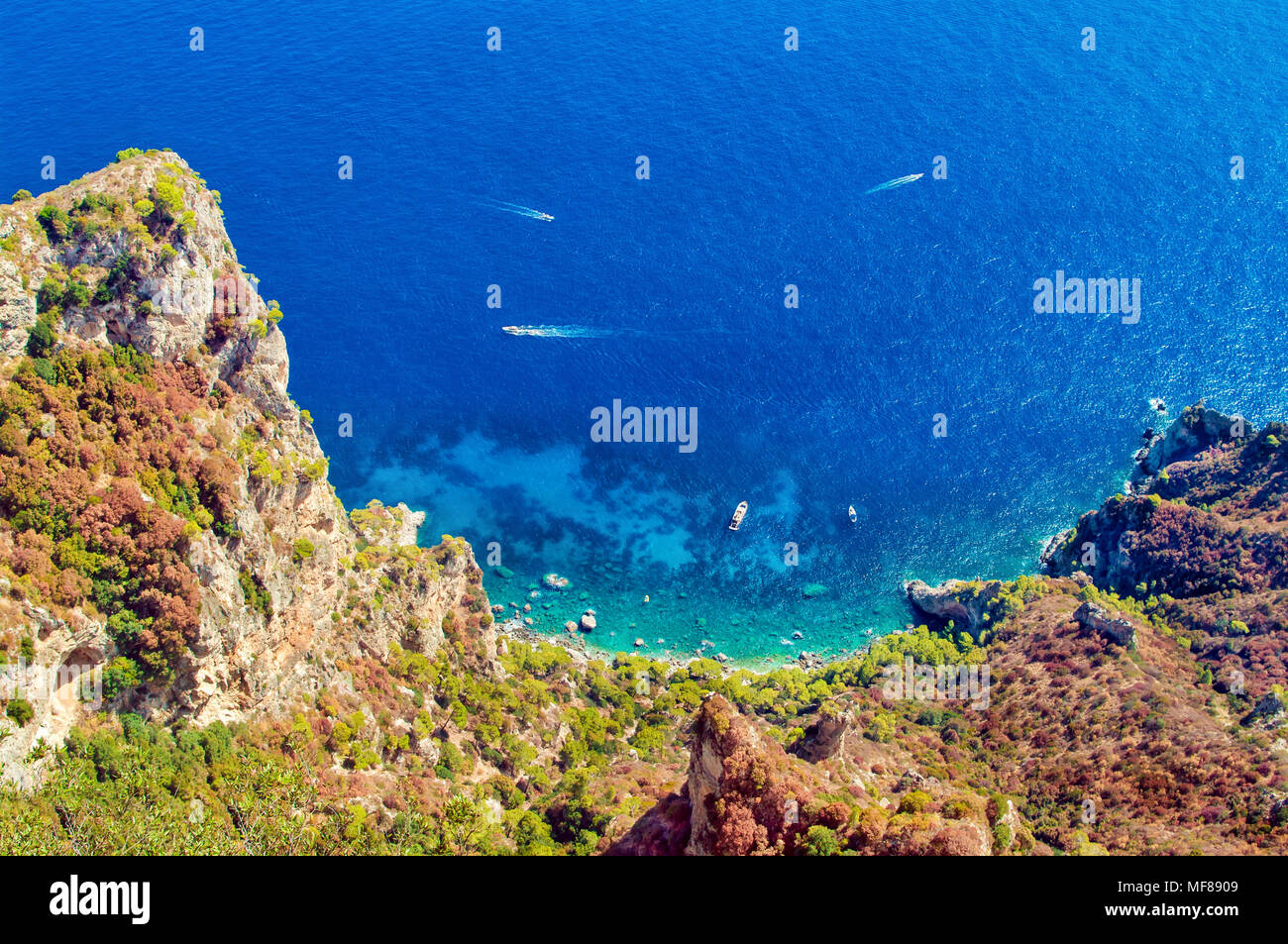 view of secluded beach with small boats and clear blue sea from rocky mountain top, Turkey Stock Photo