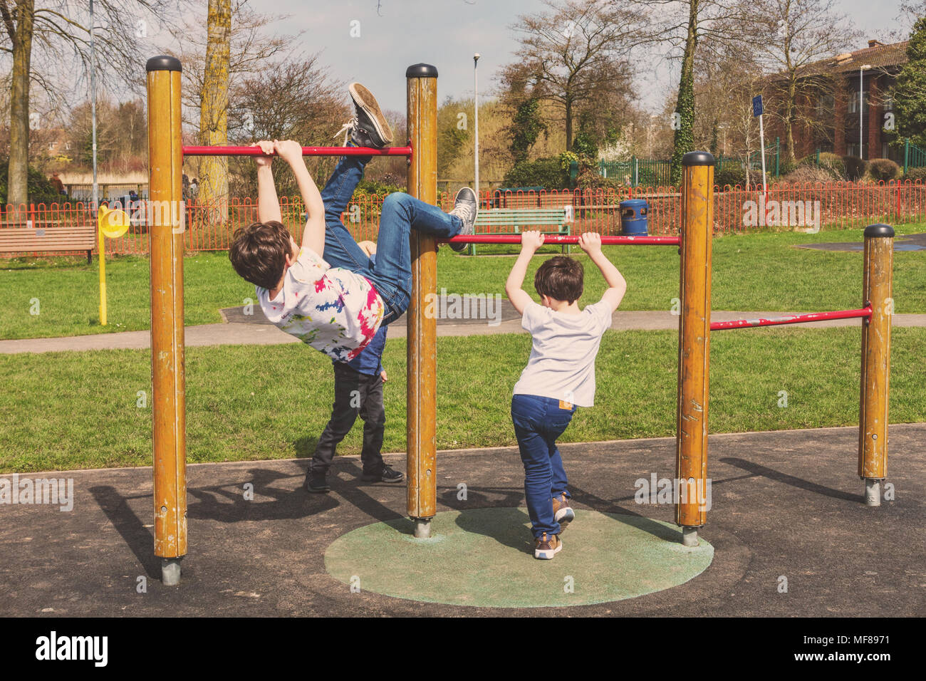 Young children play on pull up bars in a children's playground at the center of the village of Perton near Wolverhampton. Stock Photo