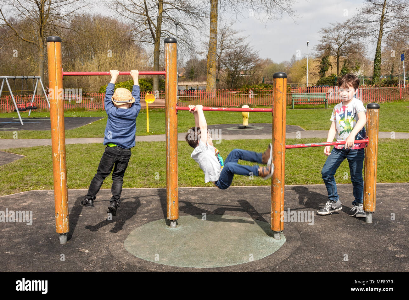 Young children play on pull up bars in a children's playground at the center of the village of Perton near Wolverhampton. Stock Photo