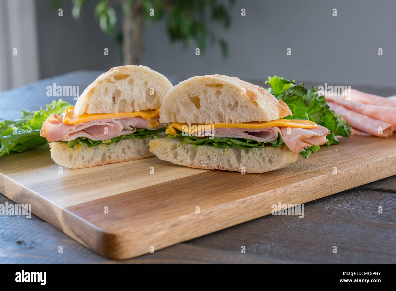 Sliced Ham and Cheese Sandwich on ciabatta roll on Cutting Board Stock Photo