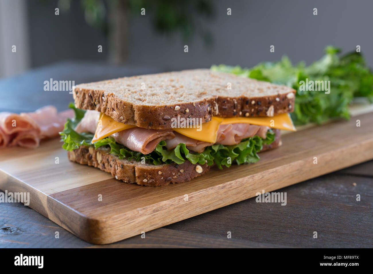 Fresh Ham and Cheese Sandwich on Whole Wheat Bread on Cutting Board Stock Photo