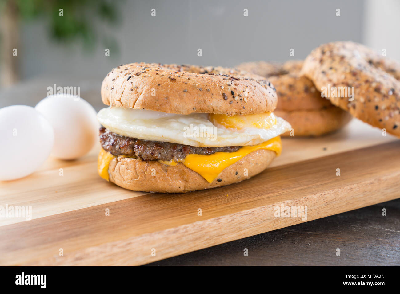 Sausage, egg and cheese breakfast sandwich with an everything bagel on cutting board Stock Photo