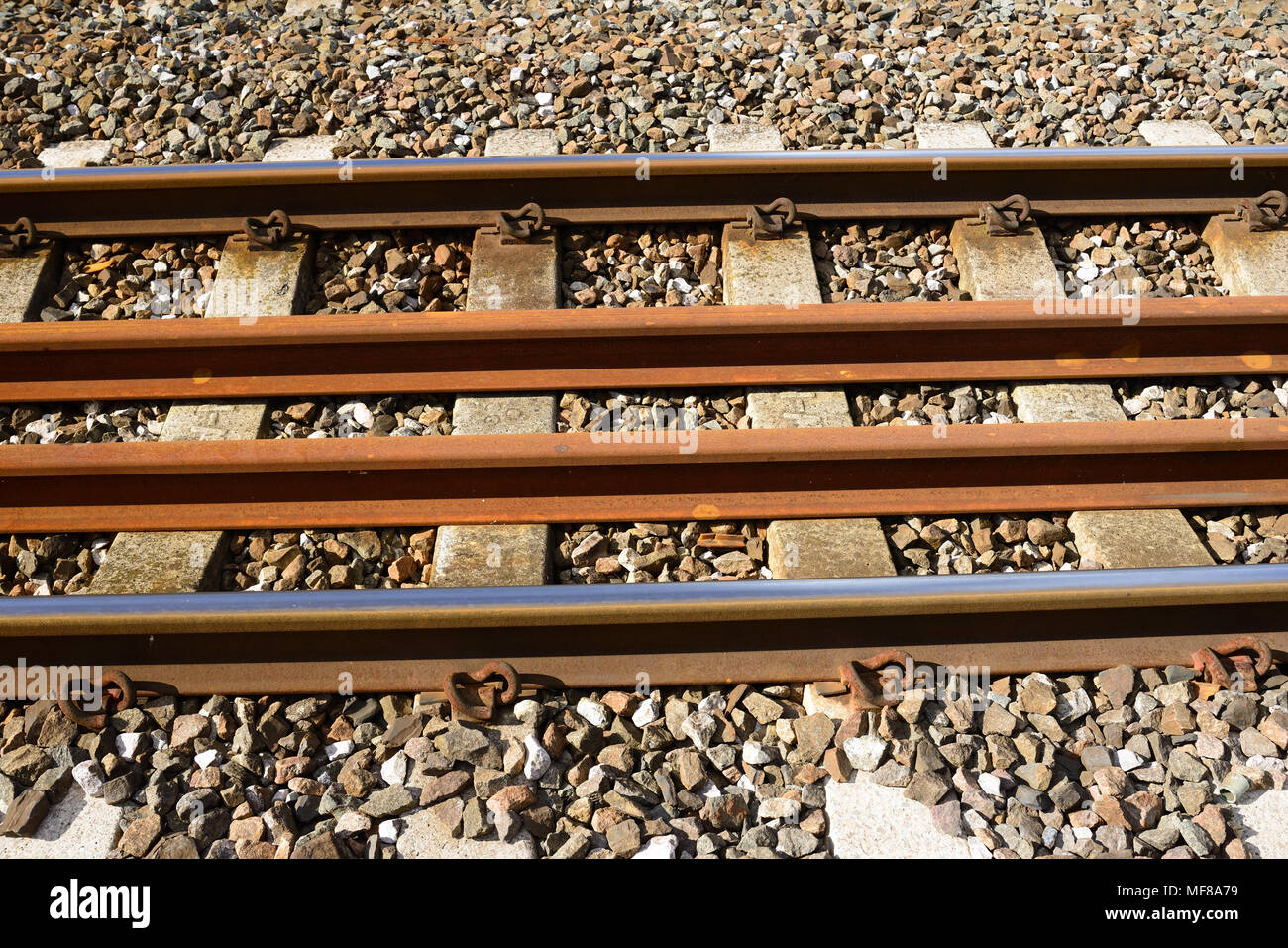 Spare long-welded rails stored between one of the running lines. Stock Photo