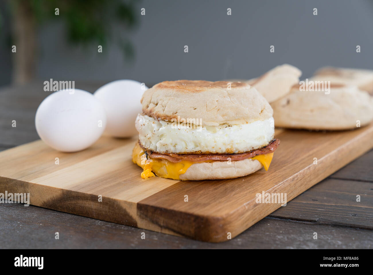 Canadian Bacon, egg and cheese breakfast sandwich with english muffin on cutting board Stock Photo