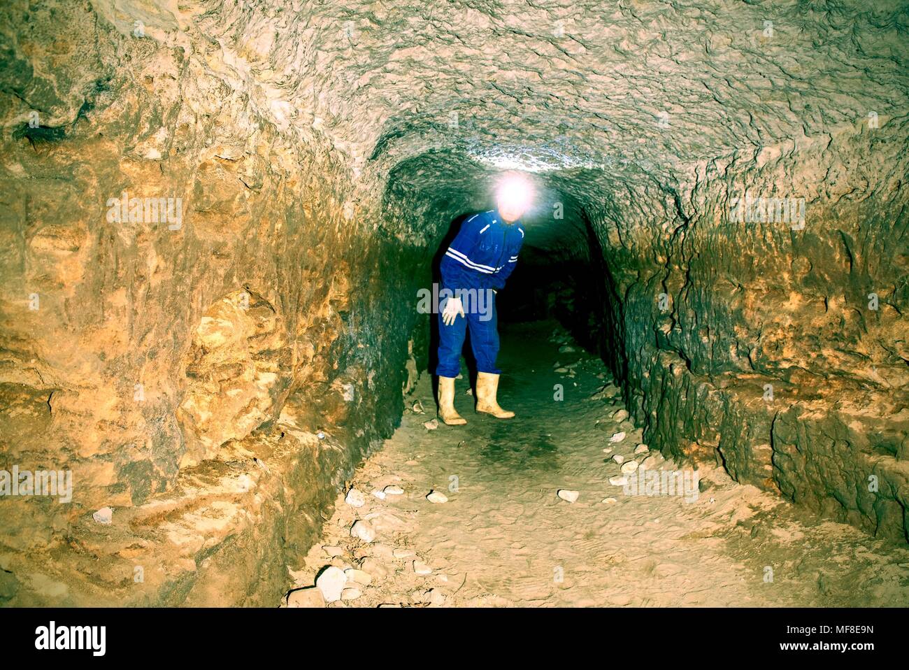 Man in underground tunnel works. Employee in safety suit works in