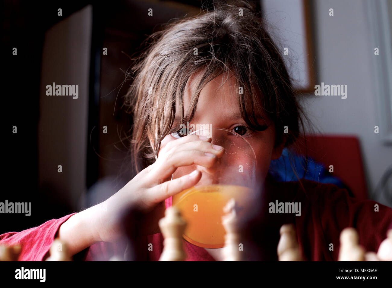 9 year old boy playing chess and drinking orange juice. Stock Photo