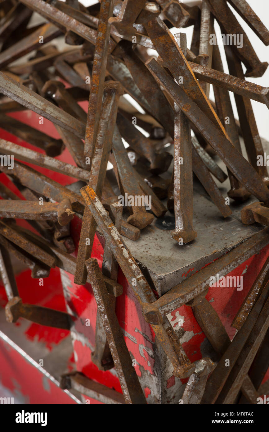 Large industrial powerful horseshoe magnet made from component parts attracting iron nails, galvanised staples, clouts demonstrating magnetic field Stock Photo