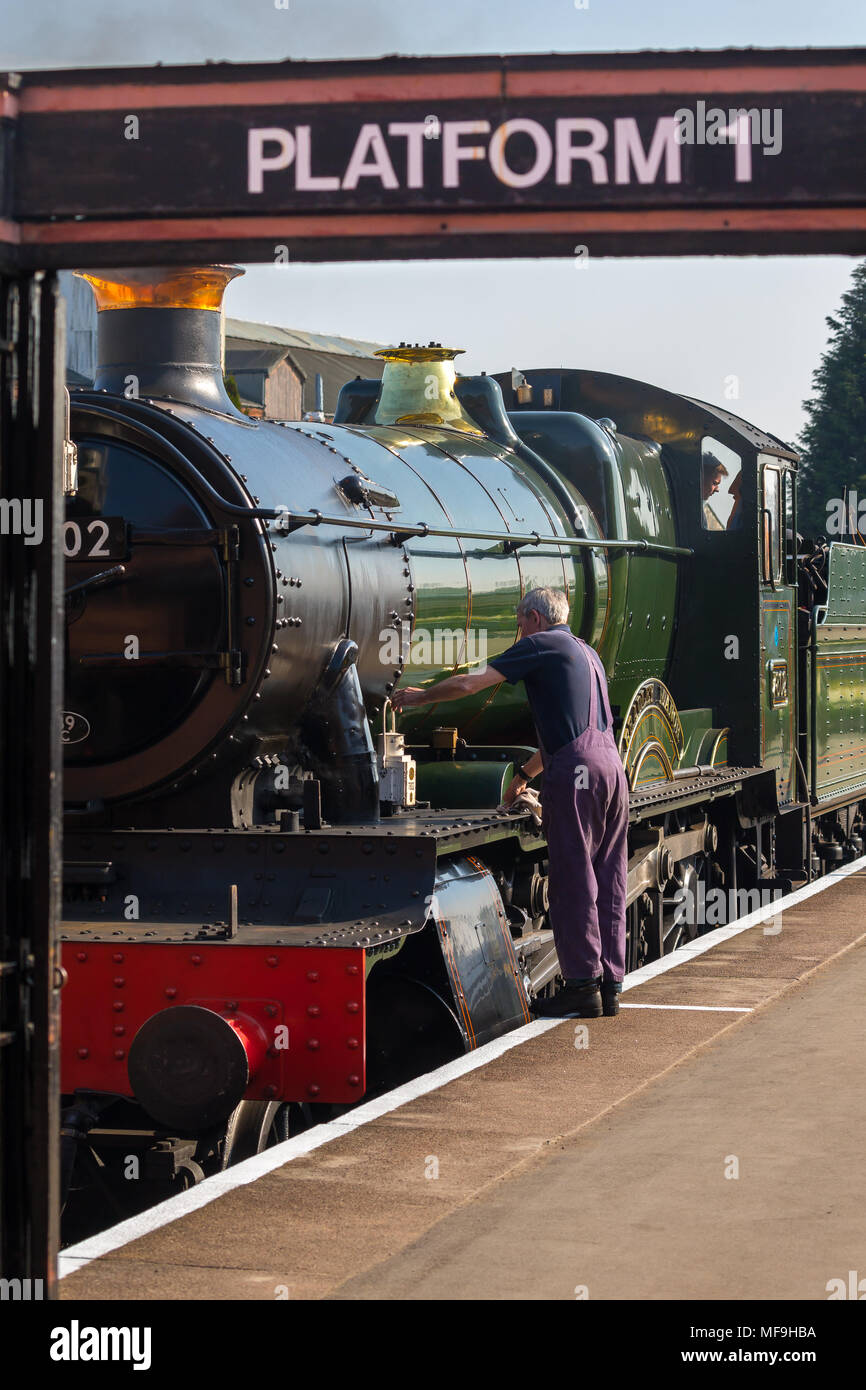 Rear view of steam train driver checking side of magnificent vintage UK