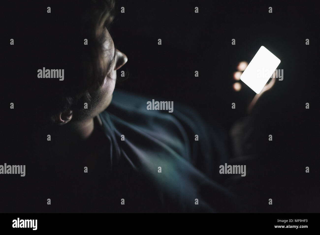 Teenage boy using smart phone in the dark Stock Photo