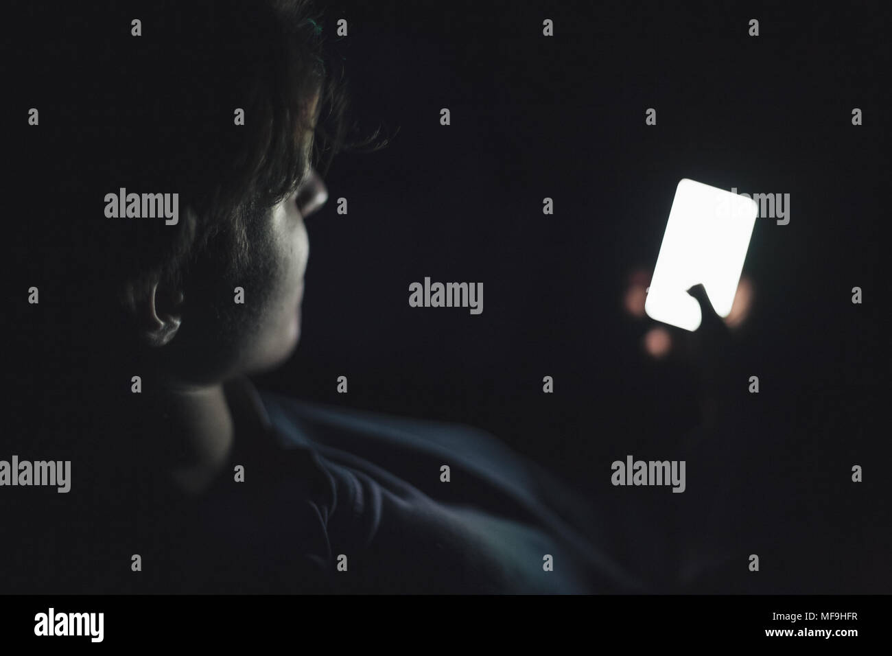 Teenage boy using smart phone in the dark Stock Photo