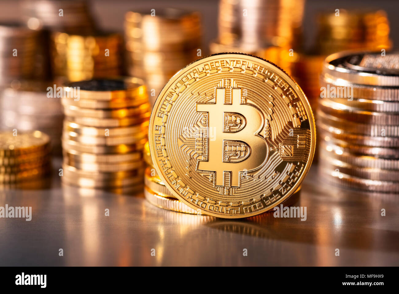 Coin of the crypto-currency Bitcoin with several stacks of coins in the background Stock Photo