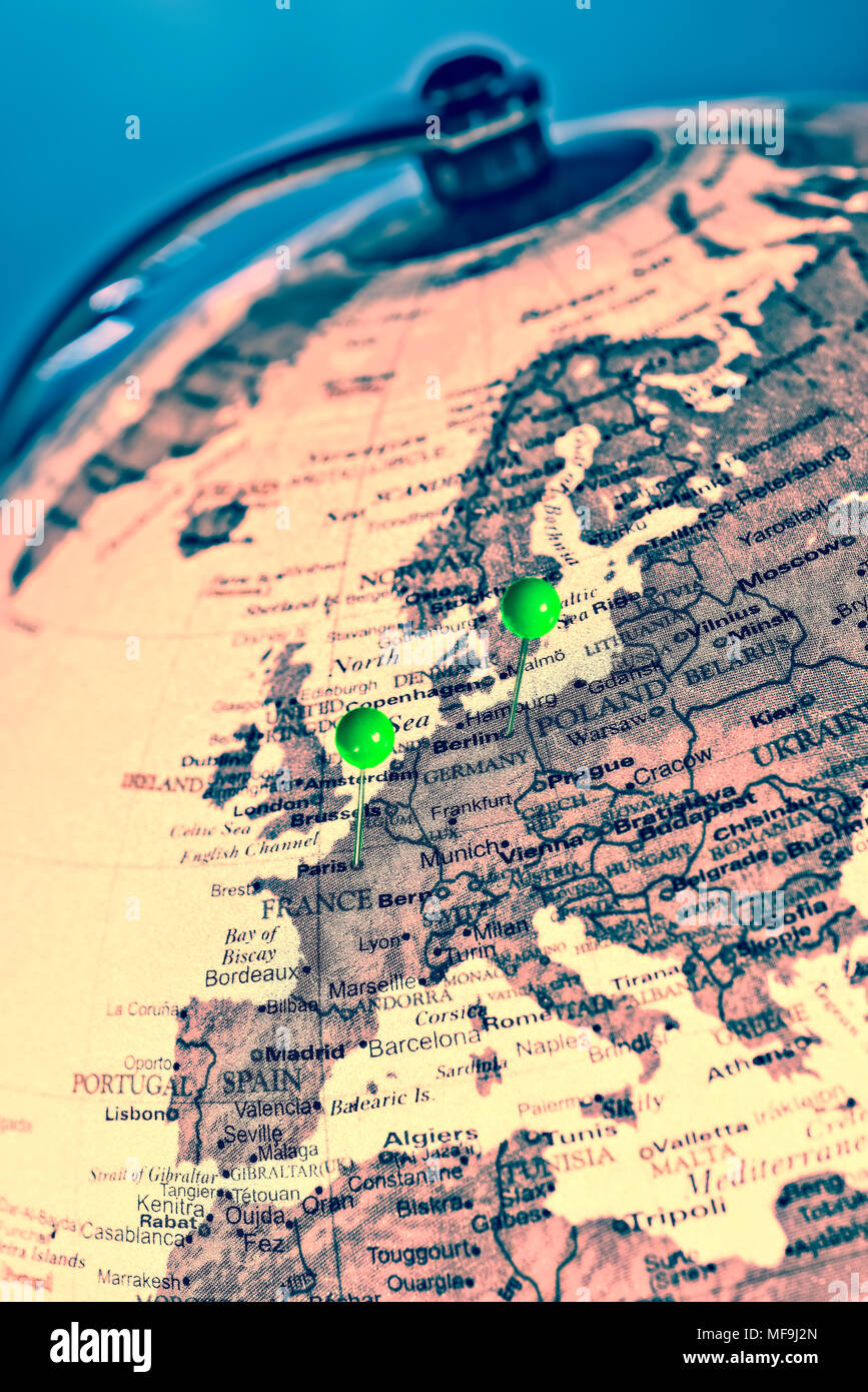 Paris and Berlin are marked with green pins on a globe Stock Photo