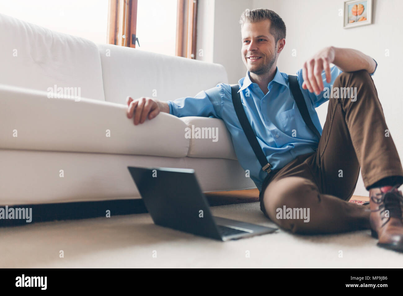 Handsome man at home in the living room using his laptop Stock Photo