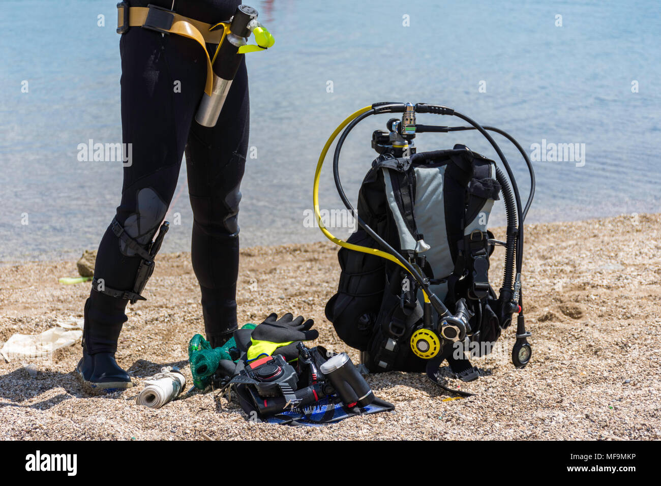 Full set of scuba diving equipment on the ground next to a sea coast