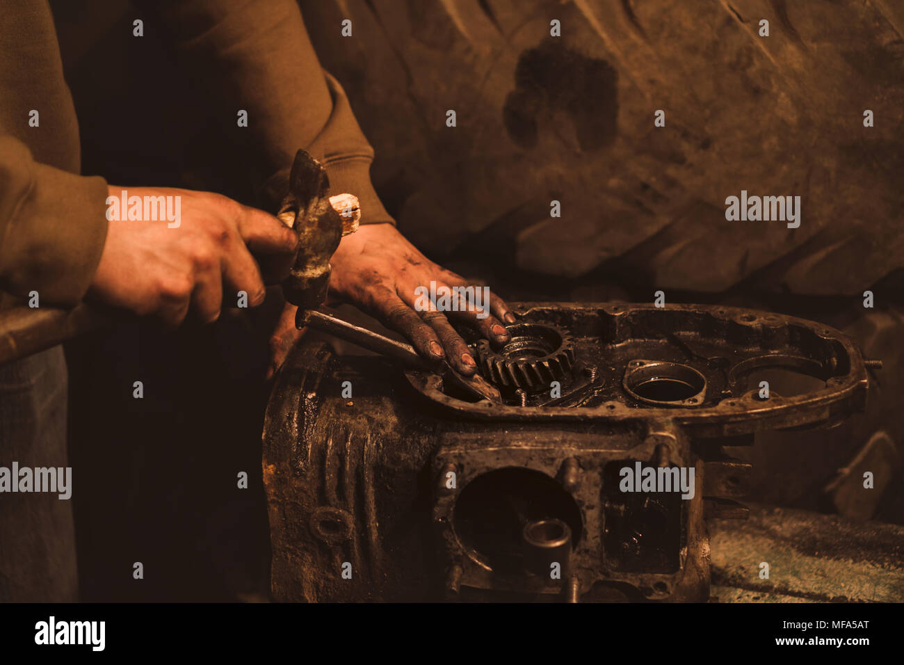 Motorcycle engine disassembly. The man takes the gear with a hammer and