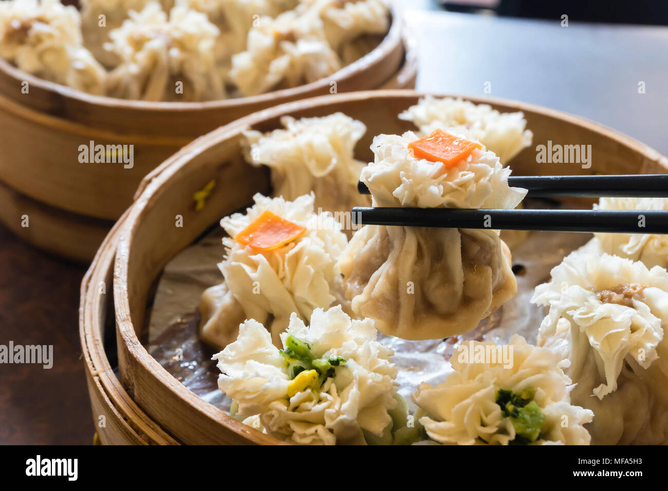Enjoying traditional Chinese dumpling called Shumai Stock Photo