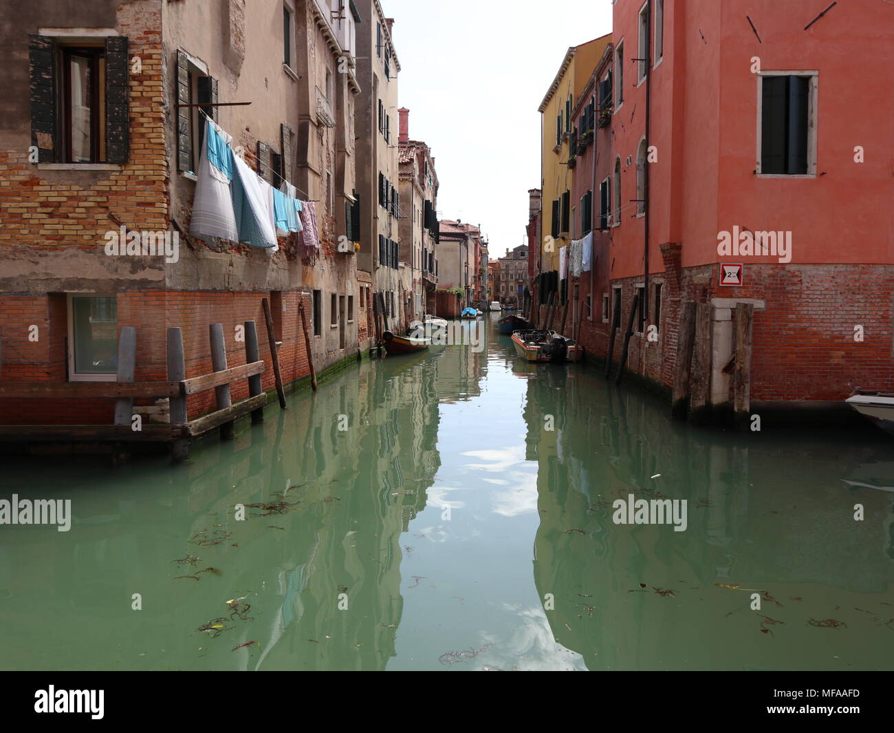 Small canal in Venice, reflection on the calm water, clothesline, picturesque scenery, Italy, Europe Stock Photo