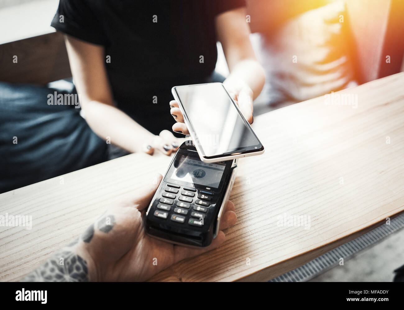 Young woman pays via payment terminal and mobile phone Stock Photo - Alamy