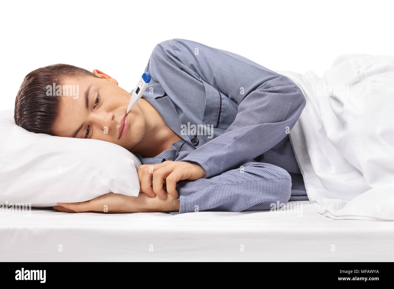 Sick teenager with a thermometer in his mouth lying in bed isolated on white background Stock Photo