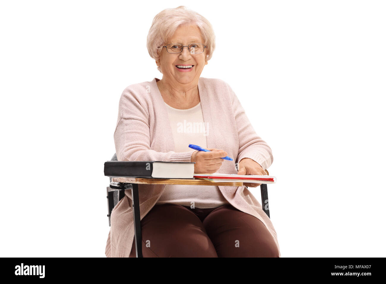 Mature woman sitting in a school chair and smiling isolated on white background Stock Photo