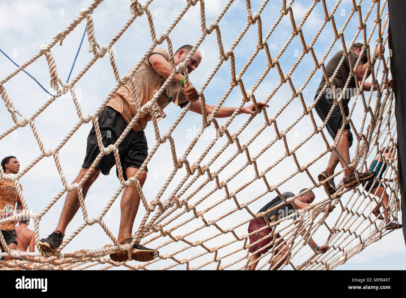 Competitors climb a cargo net on their way to the next obstacle at the Rugged Maniac Obstacle Course race on August 22, 2015 in Conyers, GA. Stock Photo