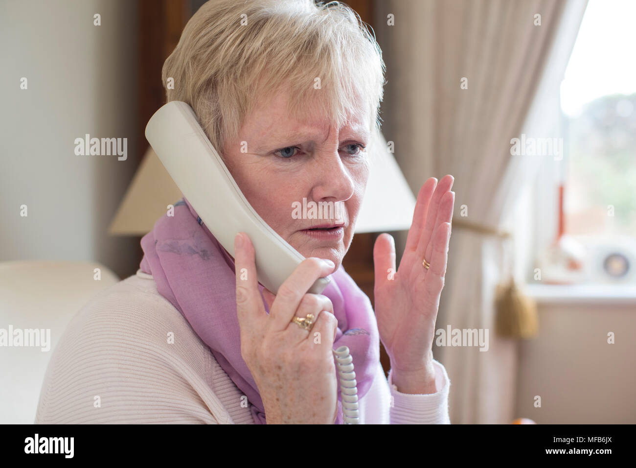 Senior Woman Receiving Unwanted Telephone Call At Home Stock Photo