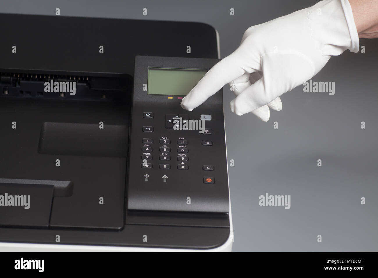 Woman's hands in white glove pressing button on control panel color laser printer in office or store Stock Photo